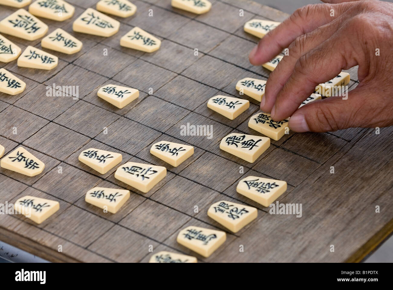 A man makes a move during a game of shogi which is similar to the Western game of chess. Stock Photo