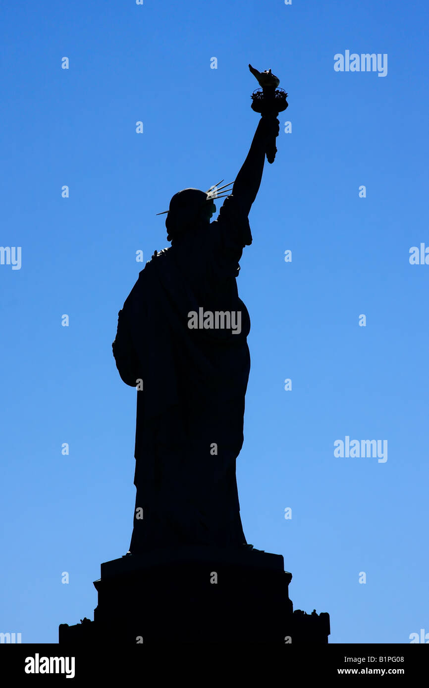 Backlit silhouette of Lady Liberty over a blue sky - New York City, USA Stock Photo