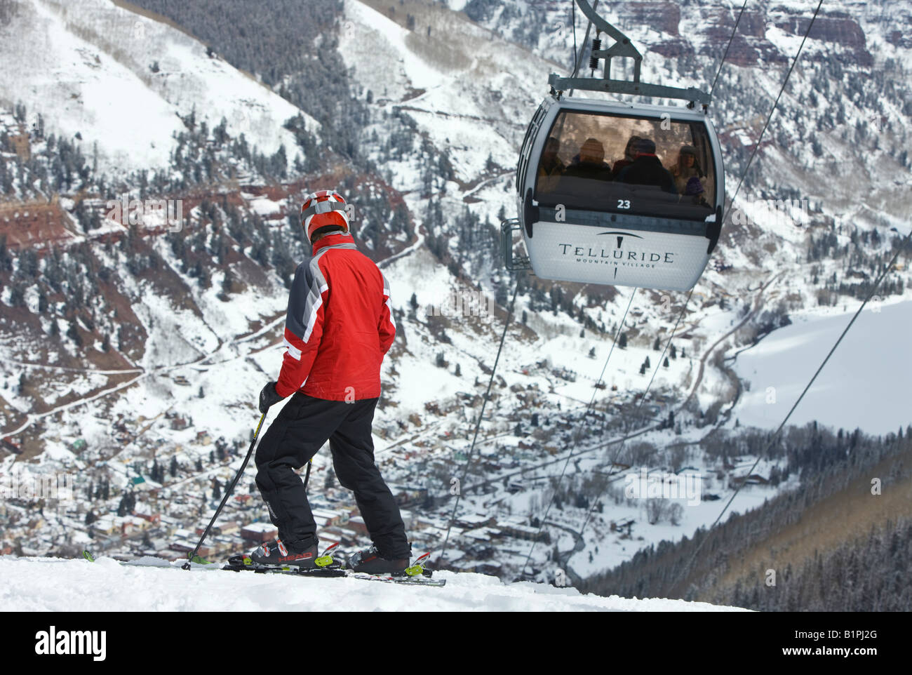 A skier watches a gondola rise above the town of Telluride at the Telluride Ski Resort, Colorado, USA. Stock Photo