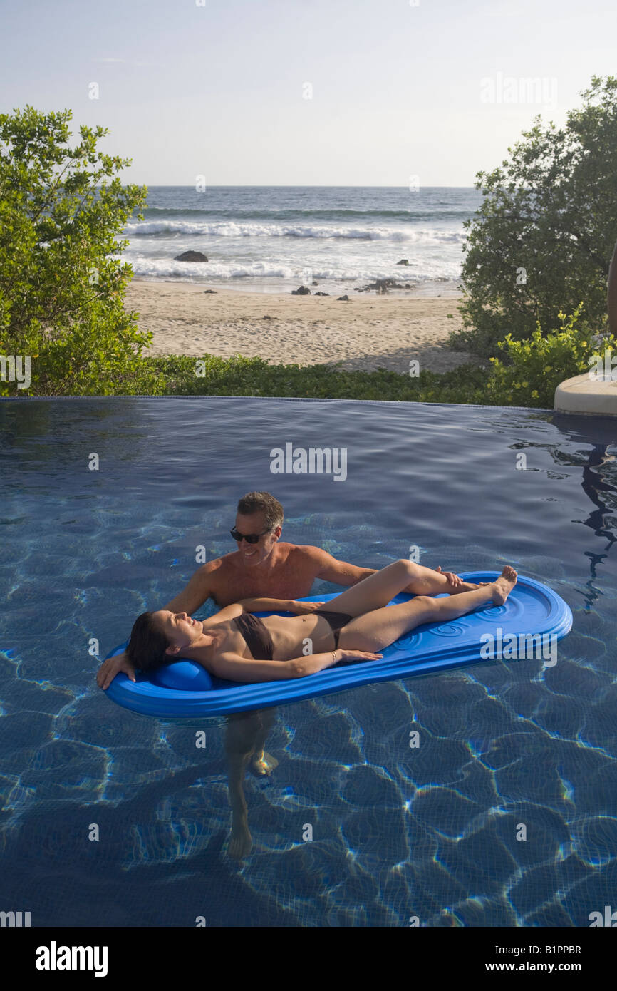 Romantic couple share a moment together in a luxurious seaside pool and villa. Stock Photo