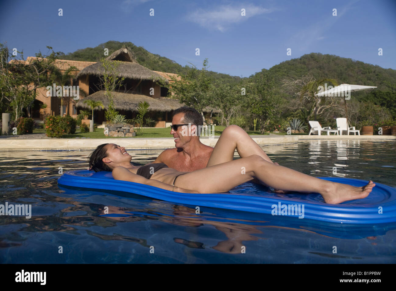 Romantic couple share a moment together in a luxurious seaside pool and villa. Stock Photo