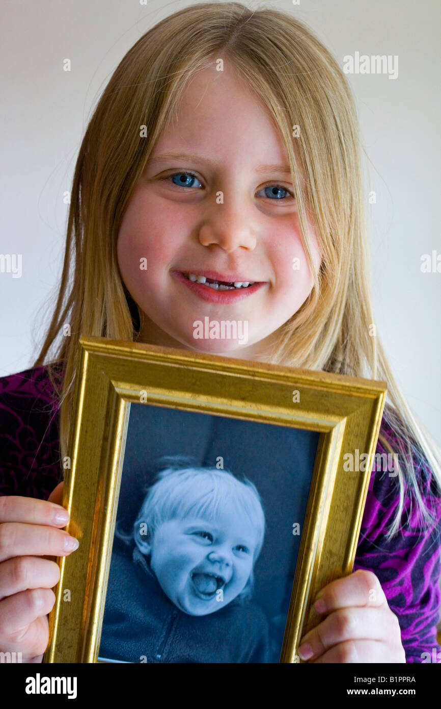 Seven year old girl holding a picture of herself as a baby showing