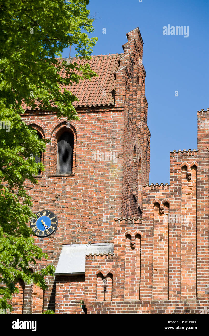 Lyngby Kirke Tower: The old red brick church dominates a hill in the centre of town Each face of the tower has a blue clock Stock Photo