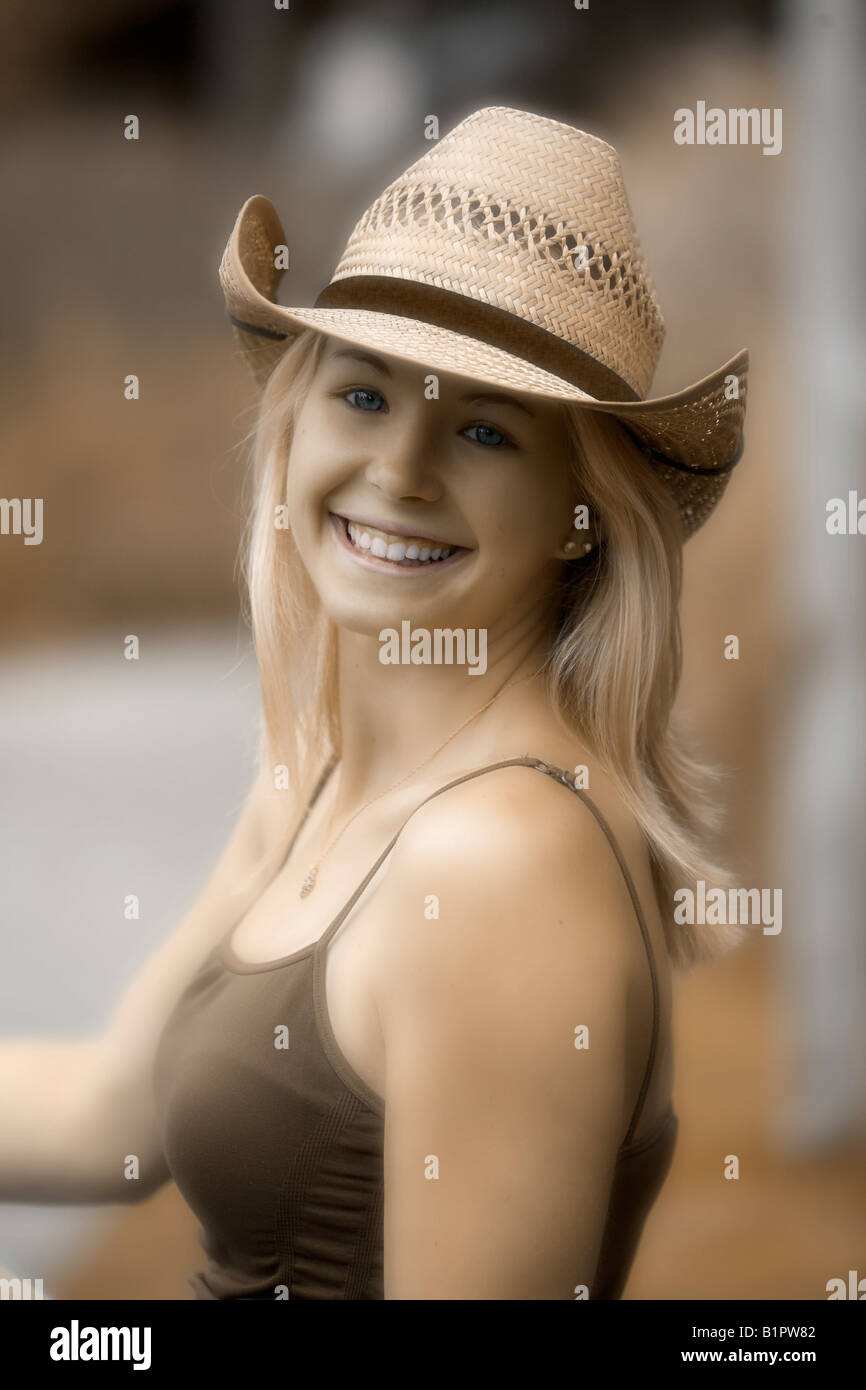 Image of a blonde Caucasian teenage girl looking back over her shoulder wearing a cowboy hat and smiling softly Stock Photo
