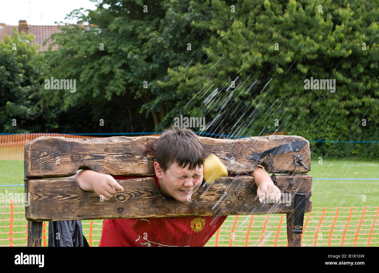 Young boy in wooden stocks being hit by a wet sponge Stock Photo