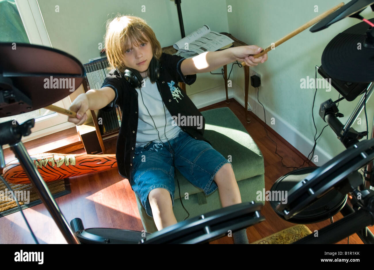 A youngster learning to play the drums with an electric drum kit Stock Photo
