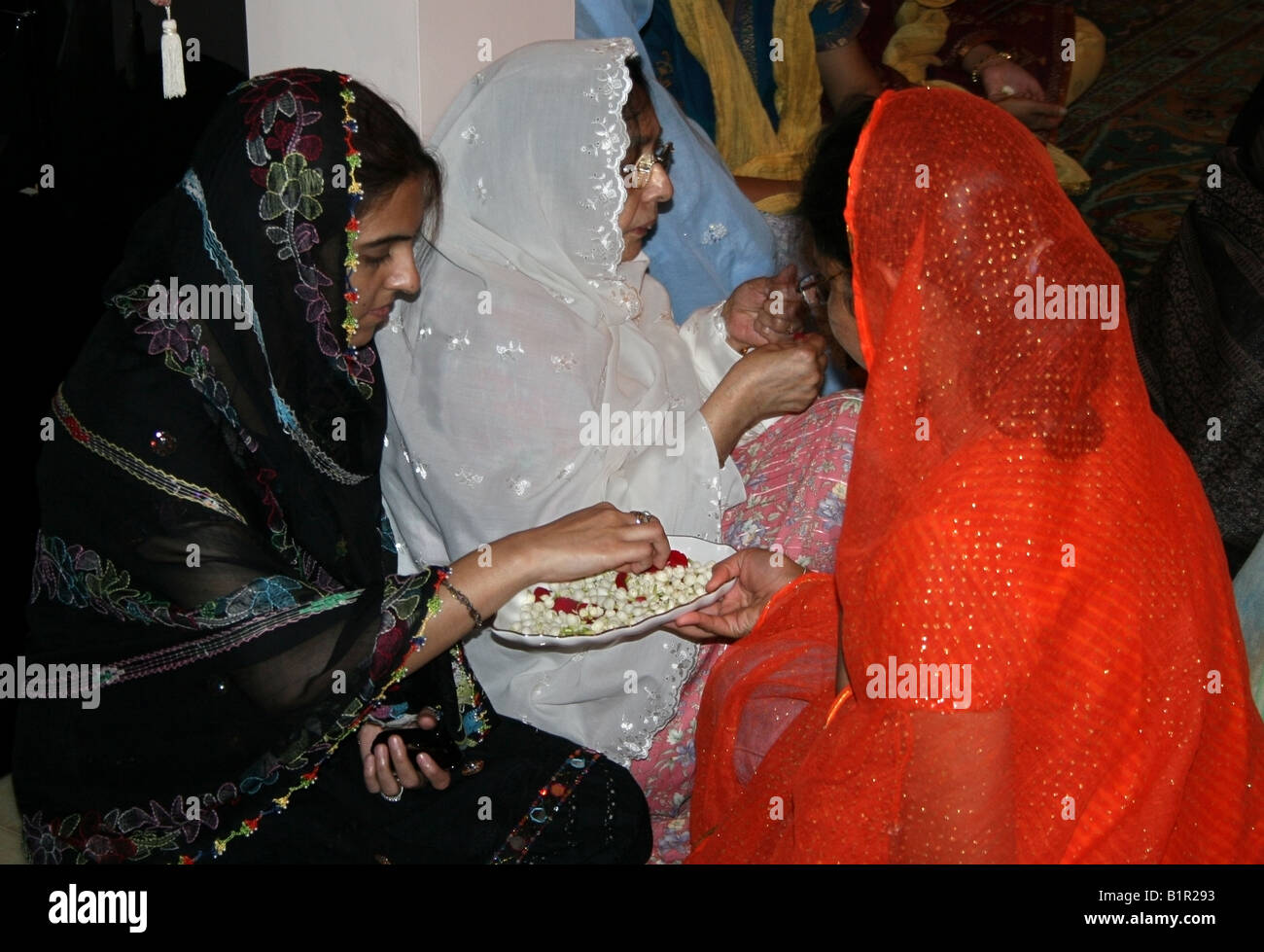Moslem woman distributes flowers at a home on the occasion of Moulid al Nabi the Prophets ( PBUH ) Birthday , India Stock Photo