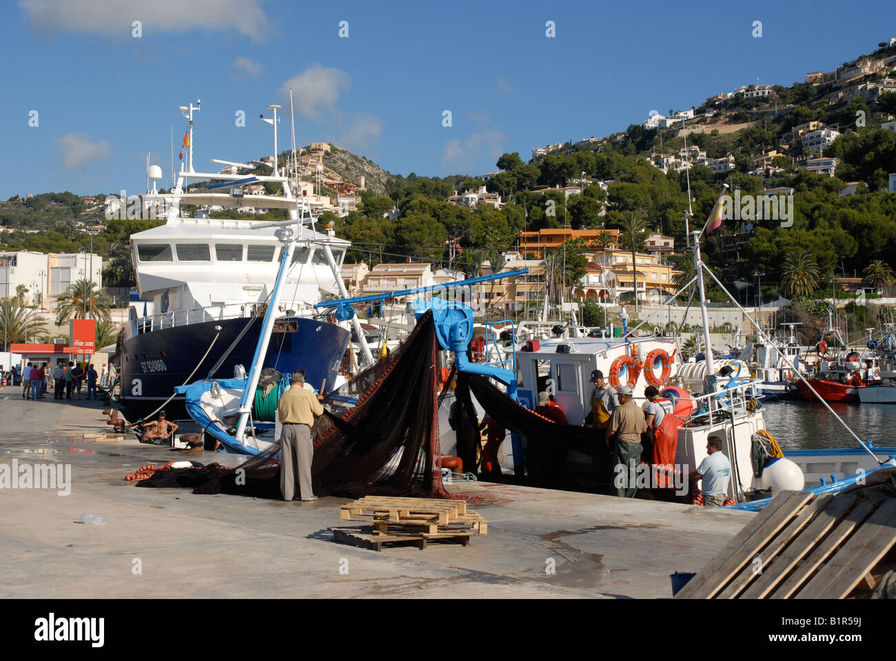 fishermen tending nets of fishing boat in the port, Javea / Xabia, Alicante Province, Comunidad Valenciana, Spain Stock Photo
