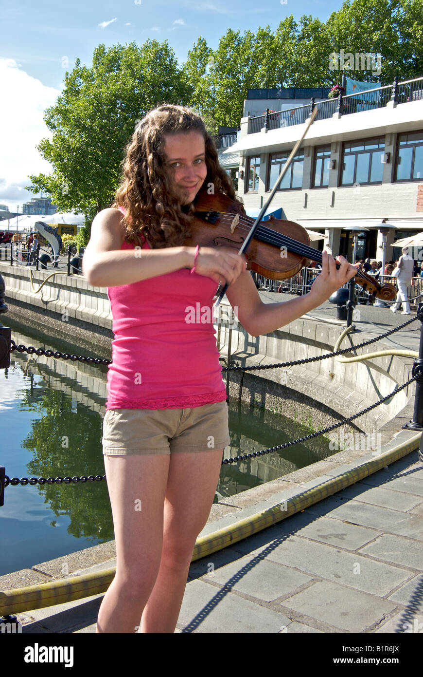 Female street musician playing a fiddle bow in motion blur on seawall walk in Victoria British Columbia Canada Stock Photo