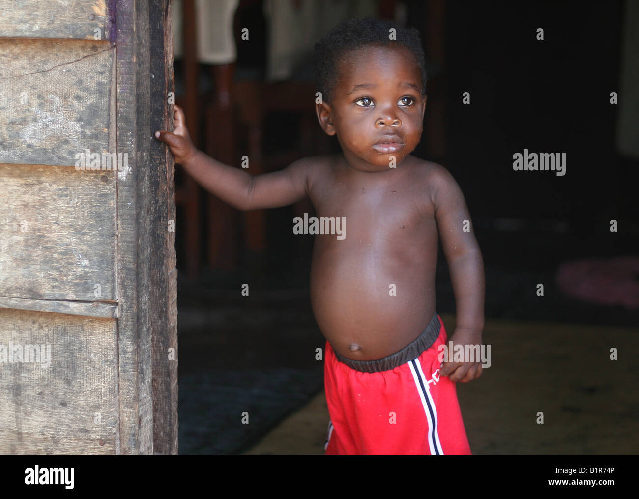 boy in front of his house, in a poor area of Paramaribo, Suriname Stock Photo