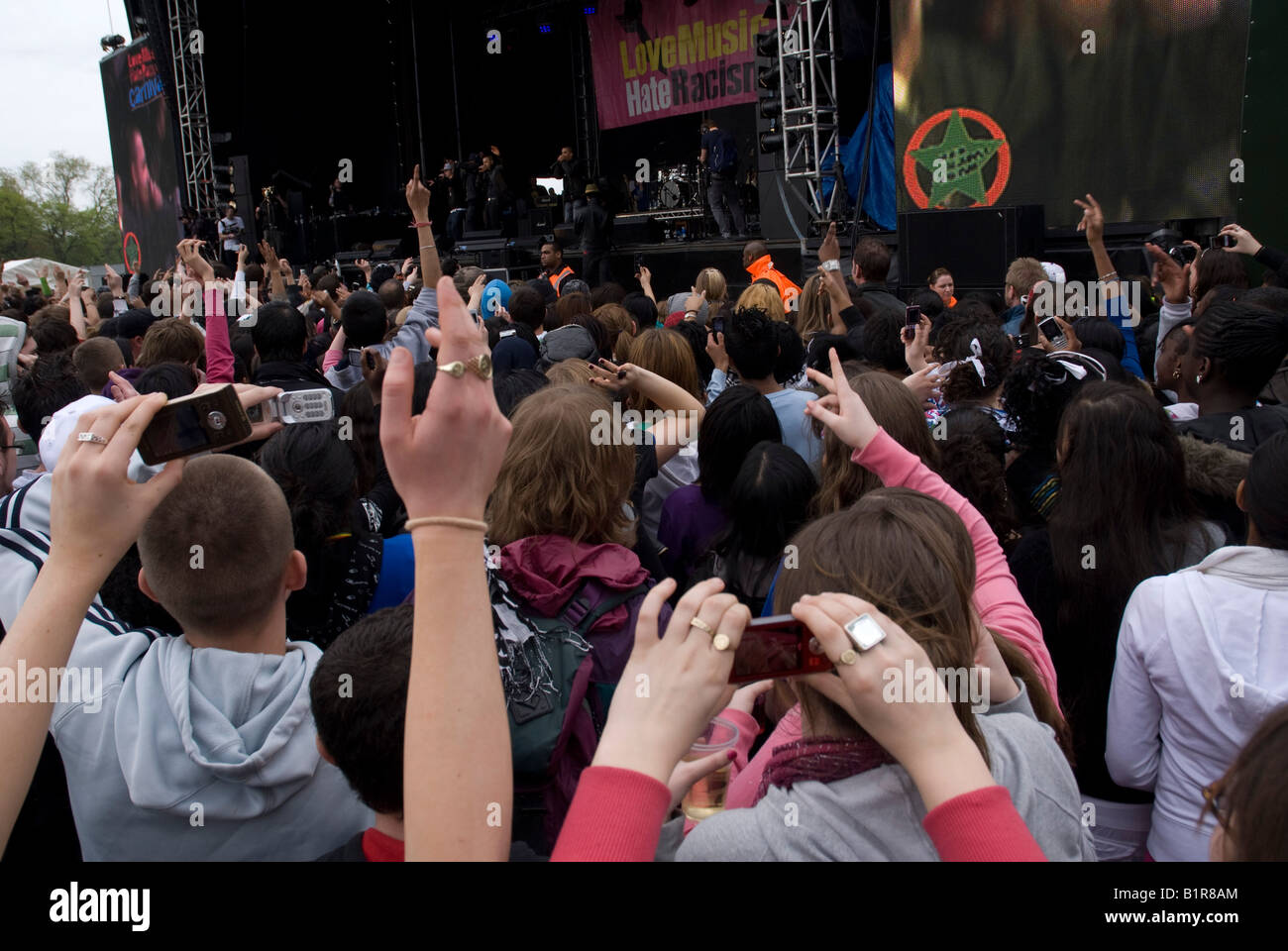 Young people hold their video mobile phones above the crowd to record a ...