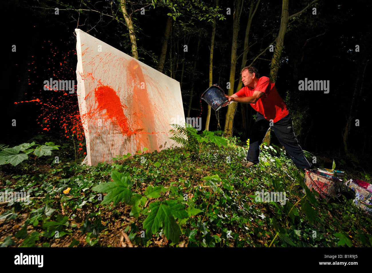 Sussex artist & illustrator David Armitage using paint thrown from buckets to create a huge abstract canvas. Picture Jim Holden. Stock Photo