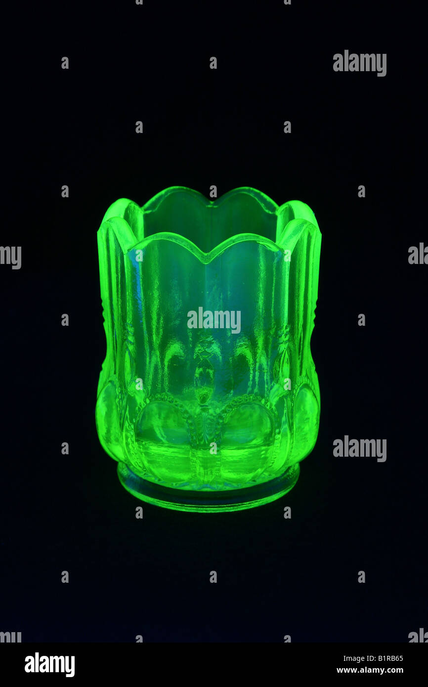 Uranium or vaseline glass toothpick jar shown under black light. Stock Photo