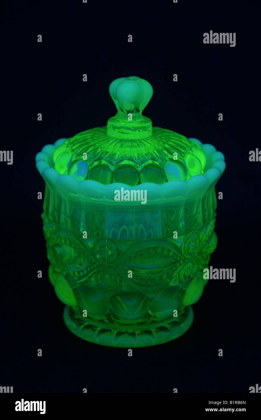 Uranium or vaseline glass sugar bowl with lid shown under black light. Stock Photo