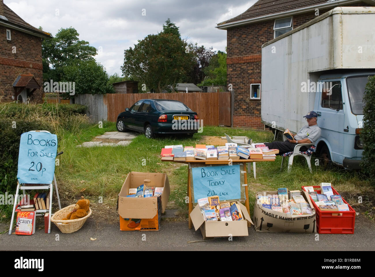 Garage sale retired man clearing out, selling off some of his books cheaply suburban London SW20 they / he are moving house. England 2005  2000s UK Stock Photo