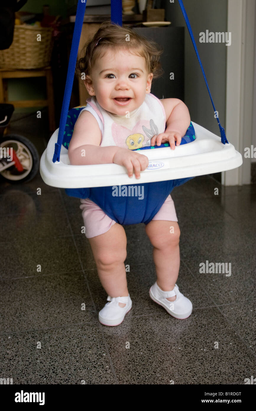 A six month baby girl jumping in a bouncer and smiling Stock Photo