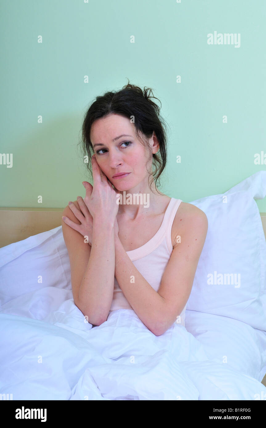 Portrait of an adult woman, crying, sad and depressed, alone in the bed of the sleeping room Stock Photo