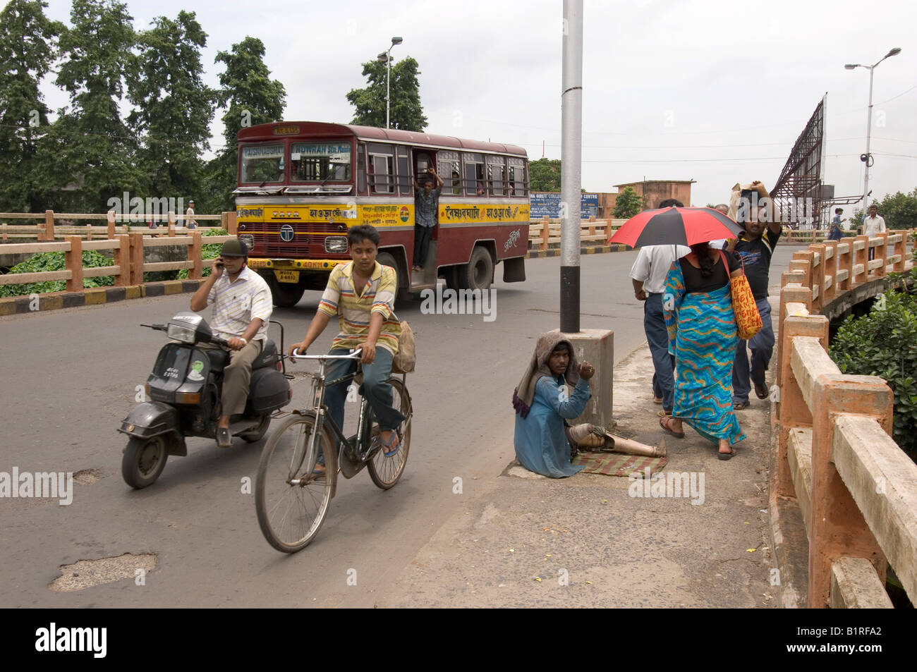 Street scene in Howrah illustrating the paradoxes within modern Indian society, crippled beggar next to the new middle class, H Stock Photo