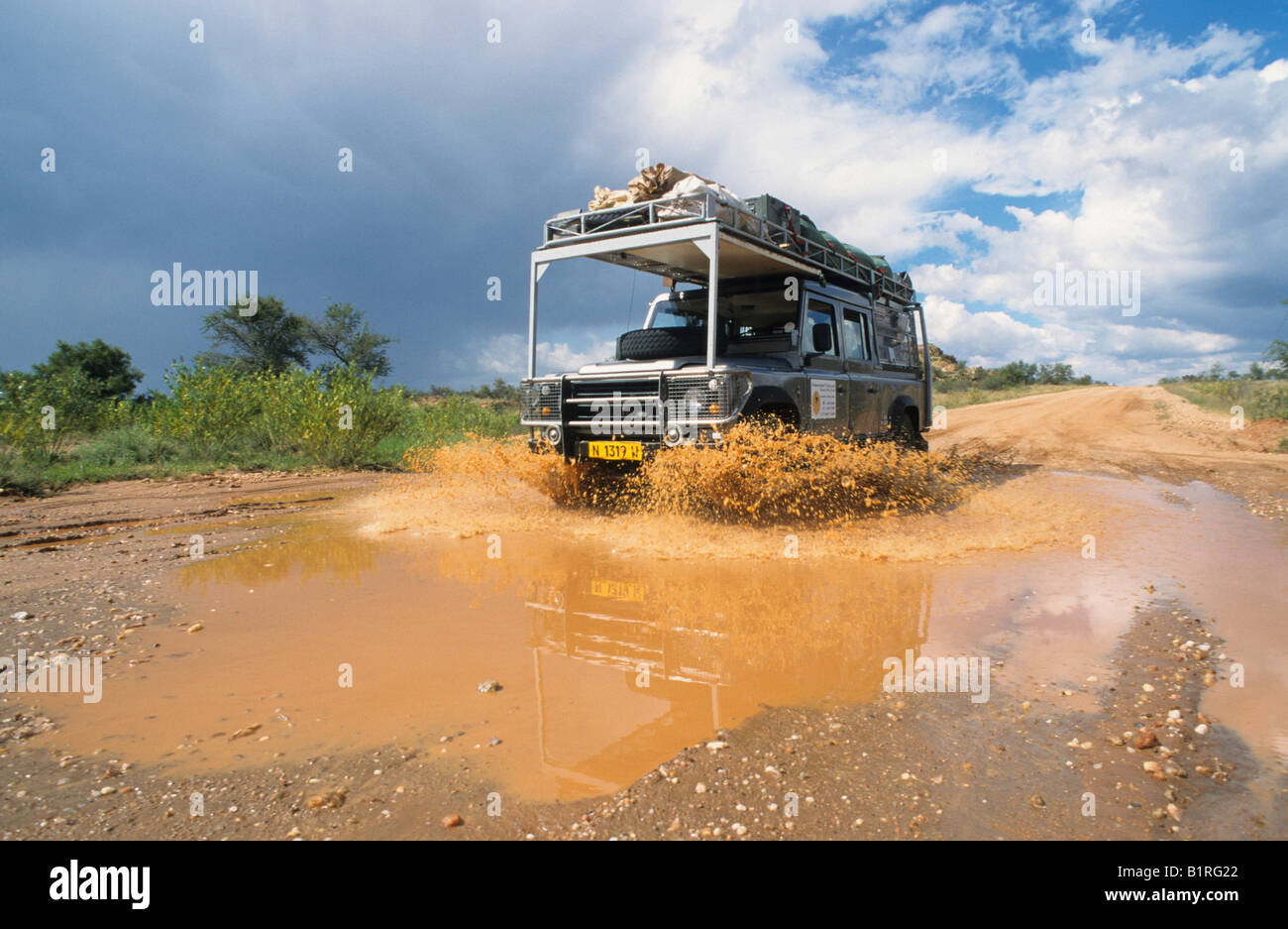 Land Rover driving through a puddle left by large amounts of rain near Omaruru, Namibia, Africa Stock Photo