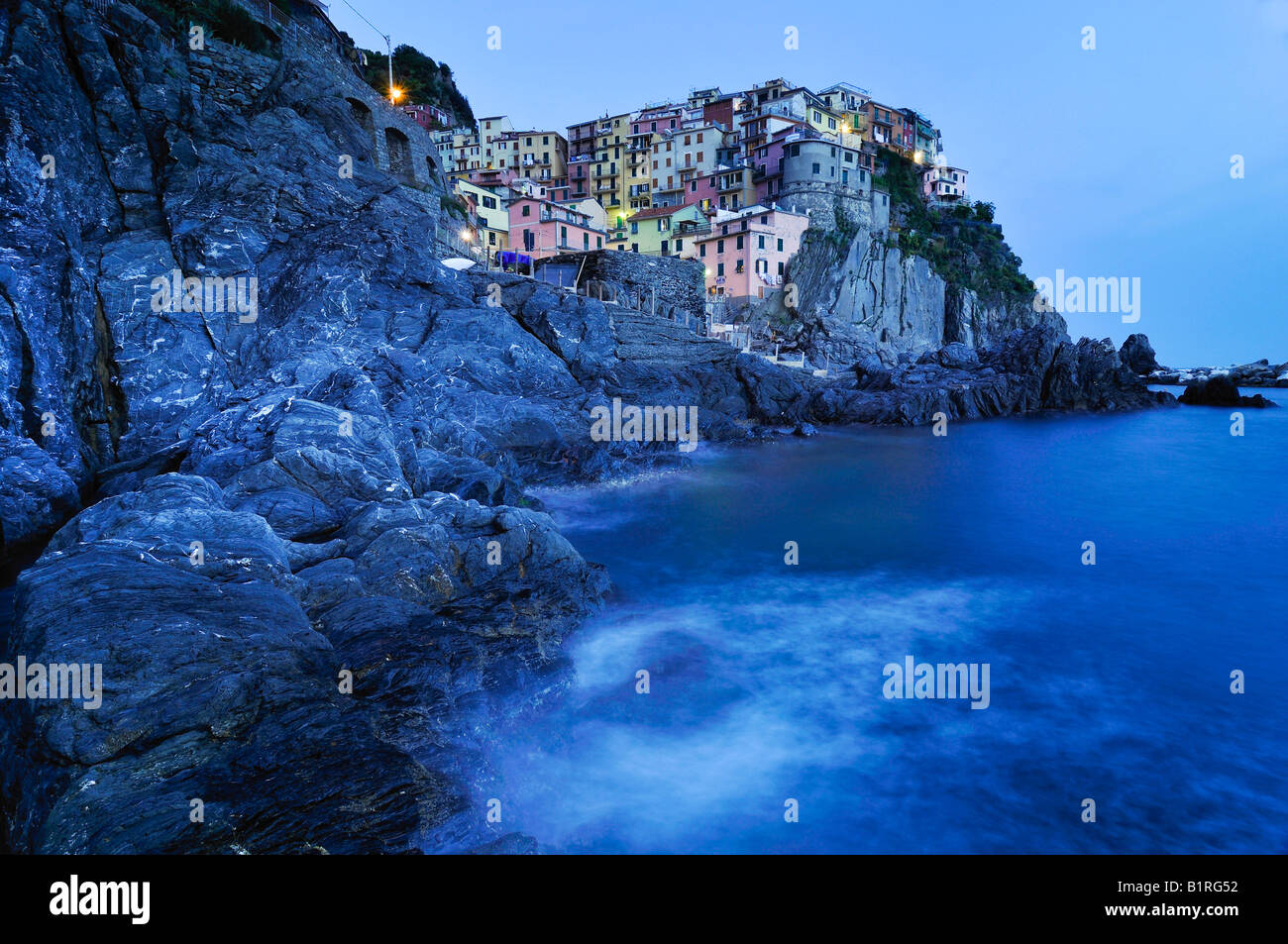 Village of Manarola nestled atop steep coastline at dusk, Liguria, Cinque Terre, Italy, Europe Stock Photo