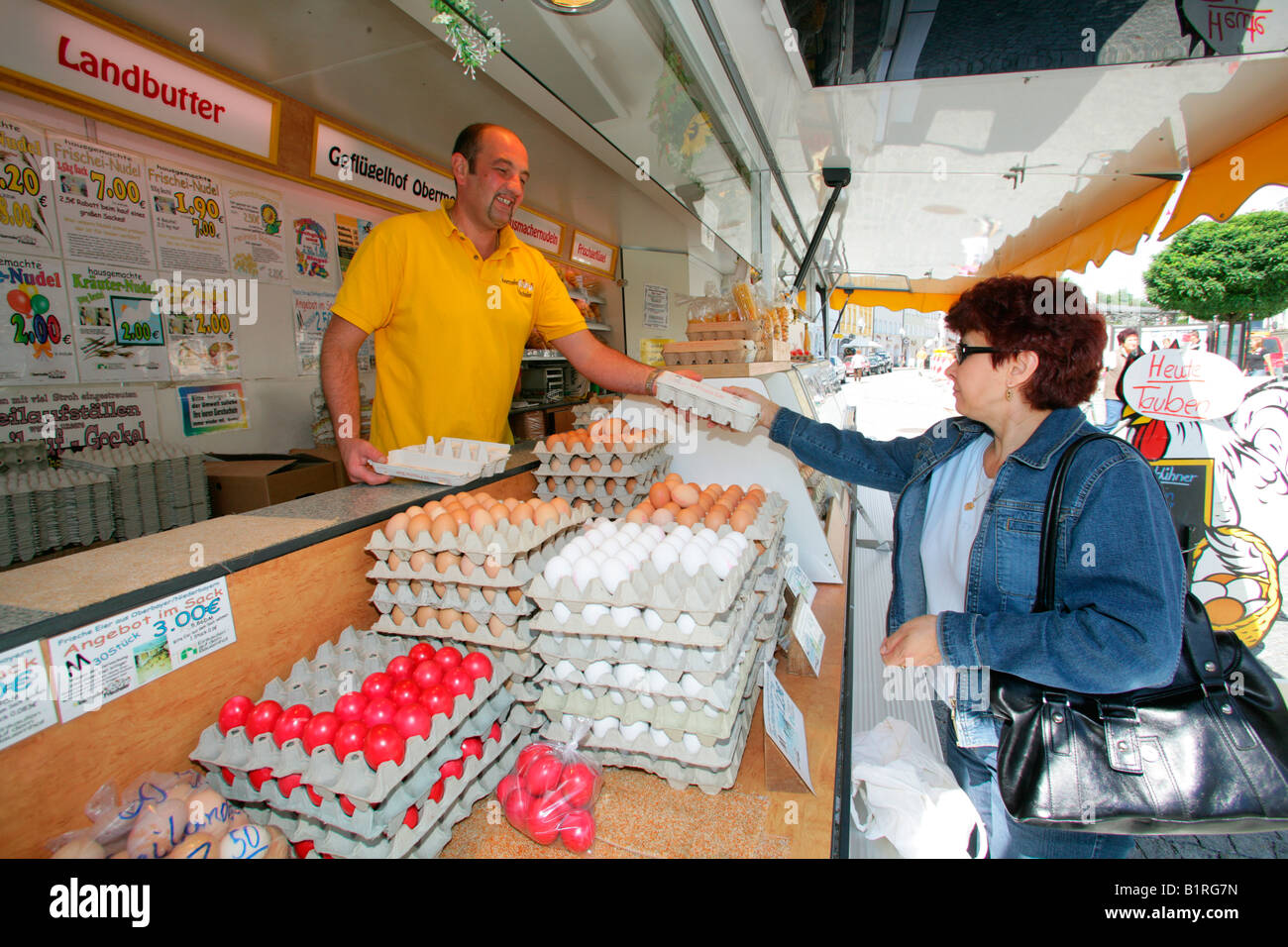 Poultry vendor handing carton of fresh eggs to a customer, weekly