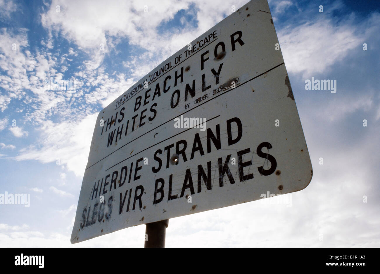 Bullet holes shot through a bilingual sign from the Apartheid era of South Africa which designates a beach as, For Whites Only, Stock Photo