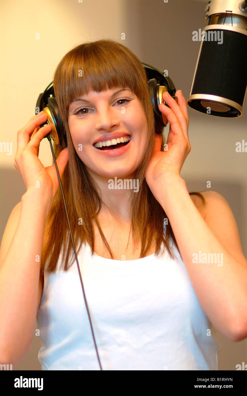 Young woman with headphones and a microphone at a recording studio Stock Photo