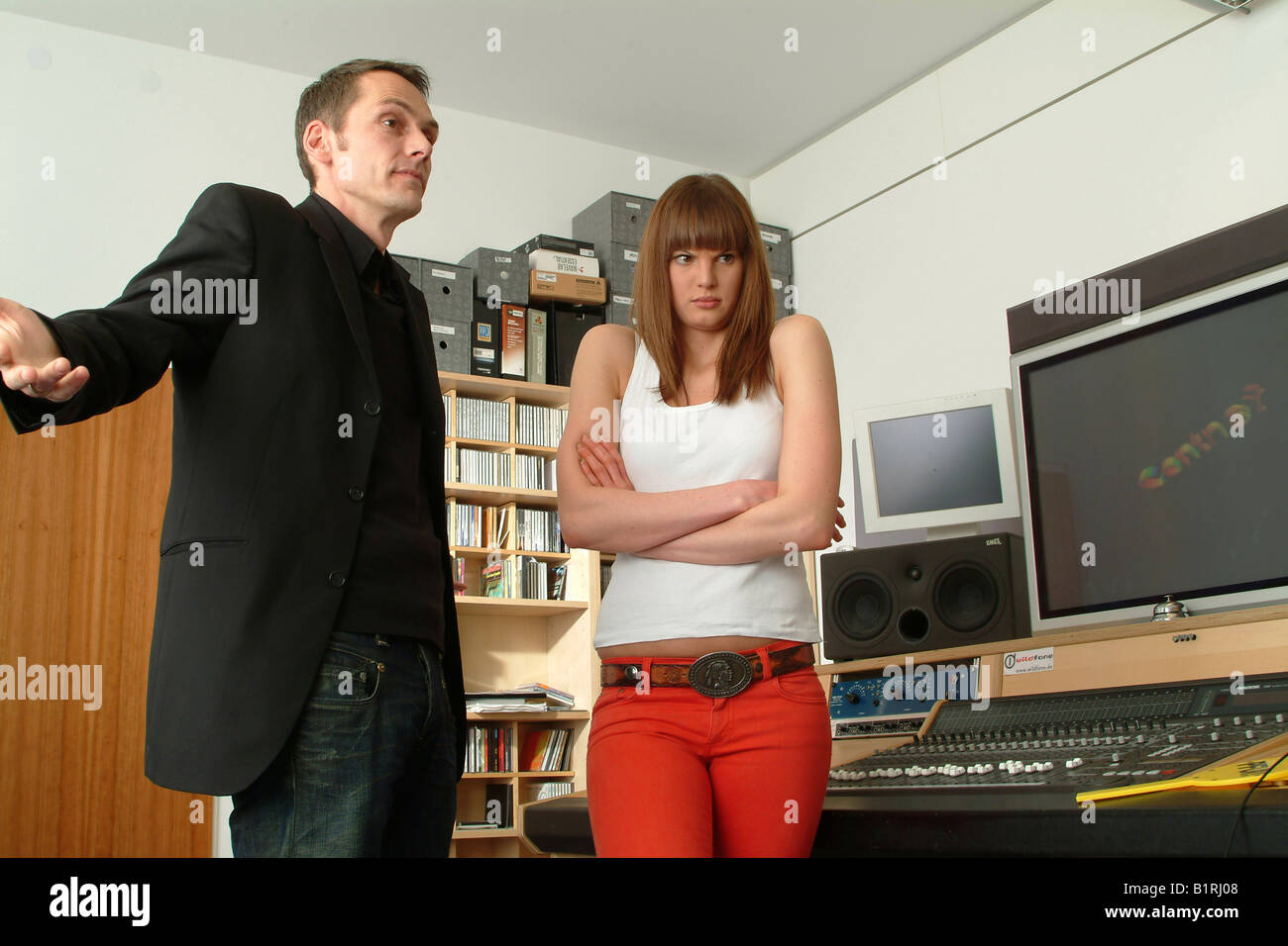 Helpless manager and angry young woman next to a mixer unit of a recording studio Stock Photo
