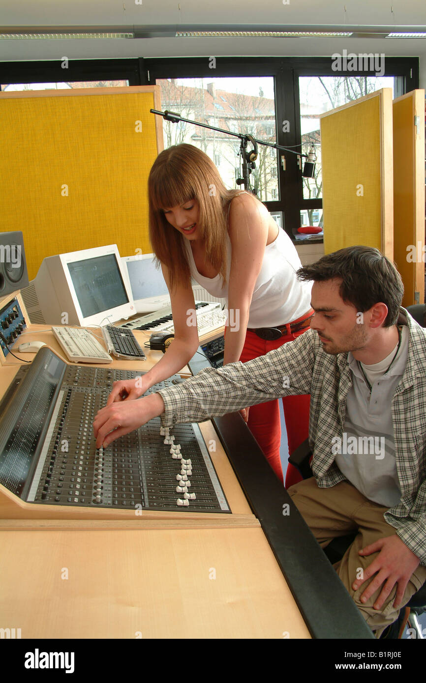 Young woman and engineer working on a mixer unit of a recording studio Stock Photo