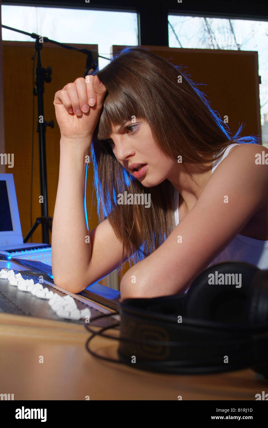 Disappointed young woman sitting at a mixer in a recording studio Stock Photo