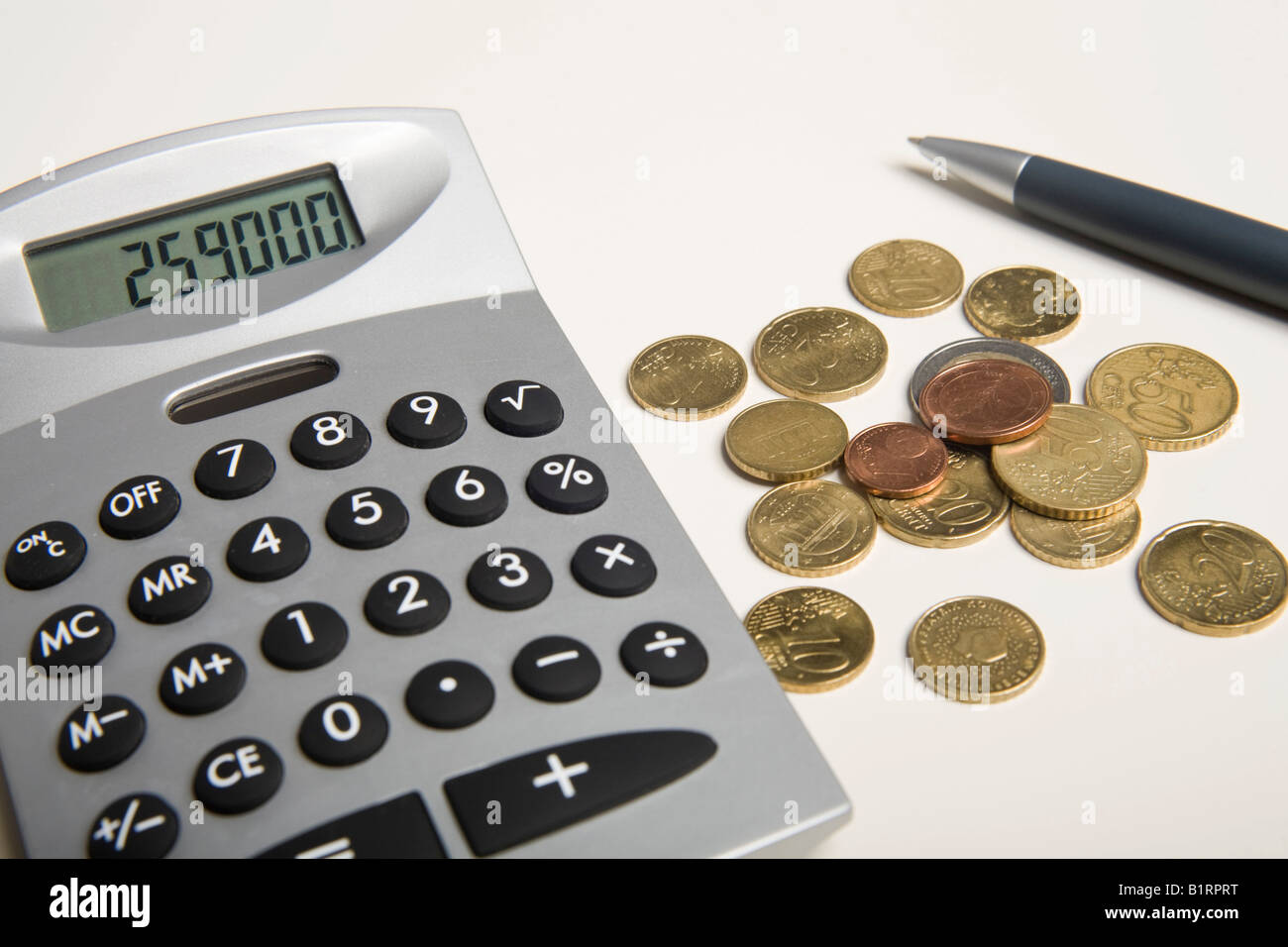 Euro coins and pen next to a calculator Stock Photo