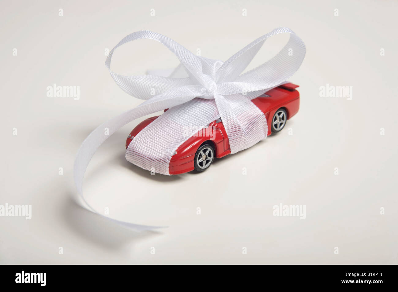 Red toy car, wrapped with a white bow as a present Stock Photo