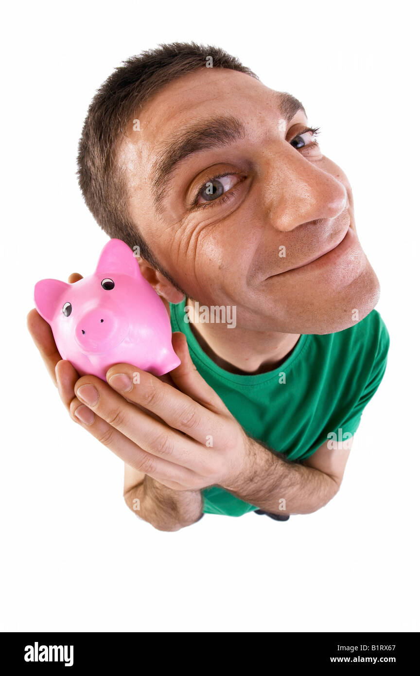 Man holding a piggy bank to his ear, fish-eye lens Stock Photo
