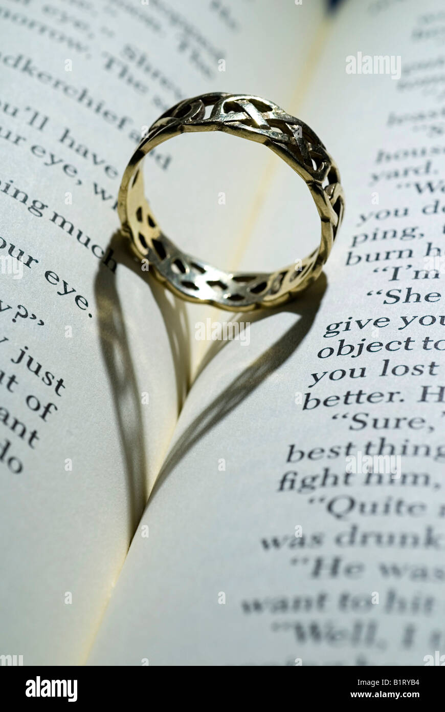 Ring lying on an open book with heart-shaped shadow Stock Photo