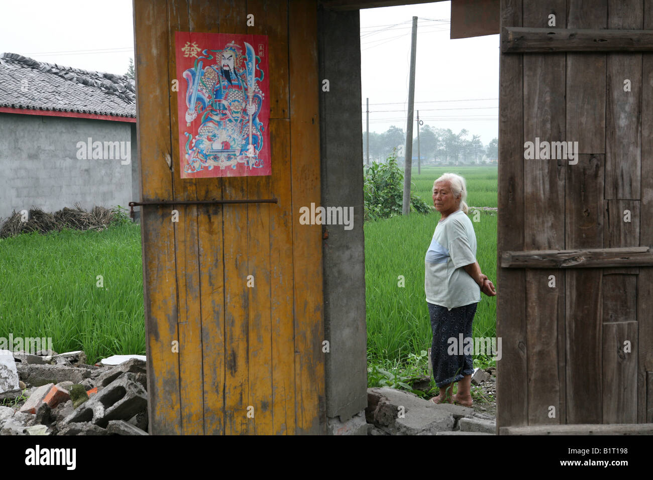 Old lady stands in front of what used to be her house in Mianzhu following the Sichuan Earthquake of 12th May 2008, China Stock Photo