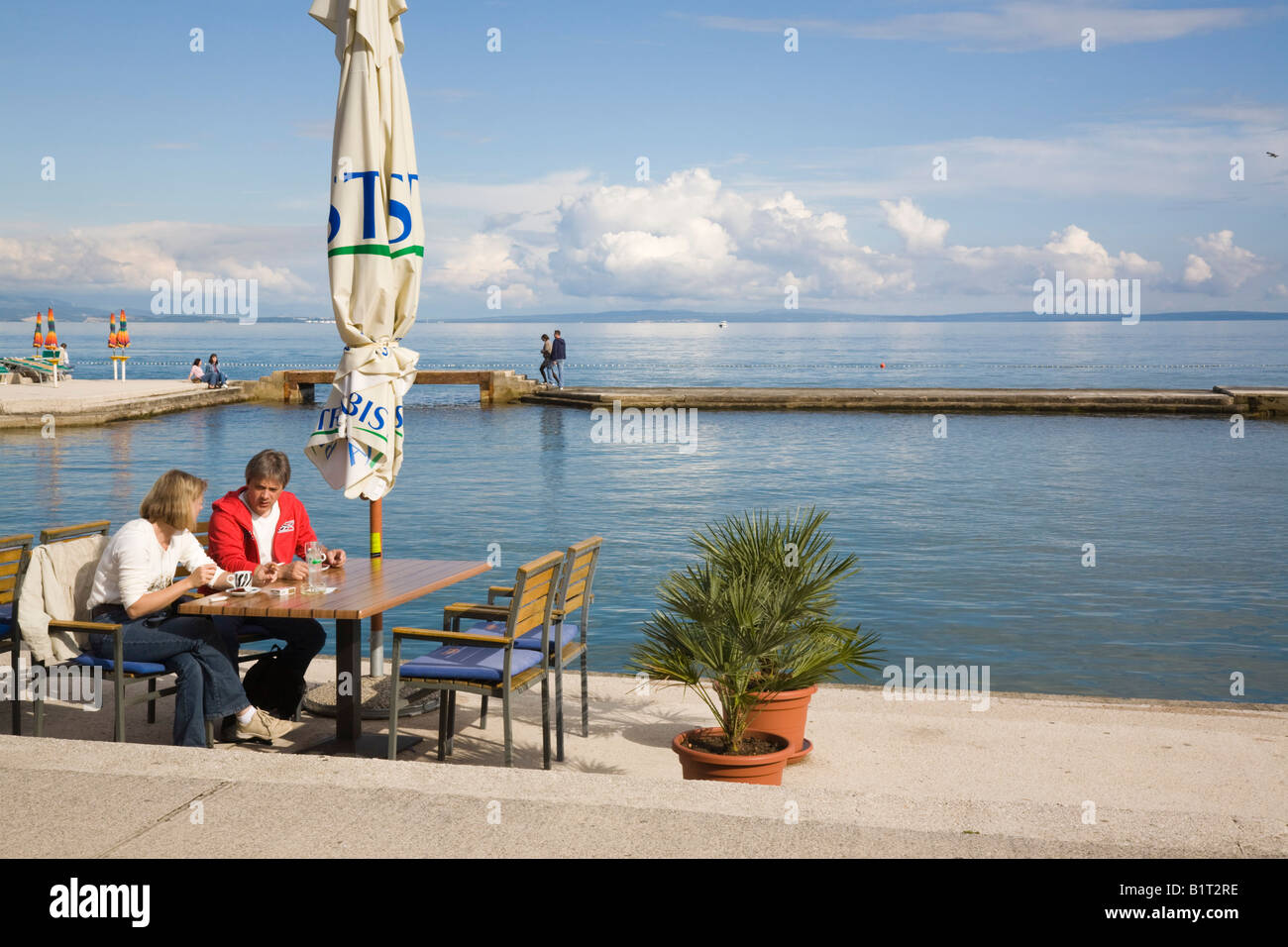 Two People In Outdoor Waterfront Restaurant By Sea In Seaside Resort On