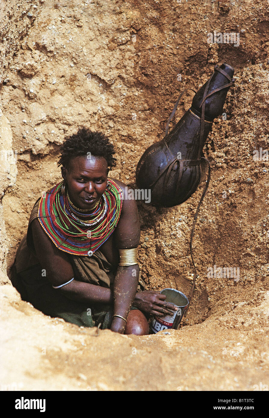 Samburu woman bailing water into gourds at bottom of deep waterhole Serolevi Northern Kenya East Africa Stock Photo