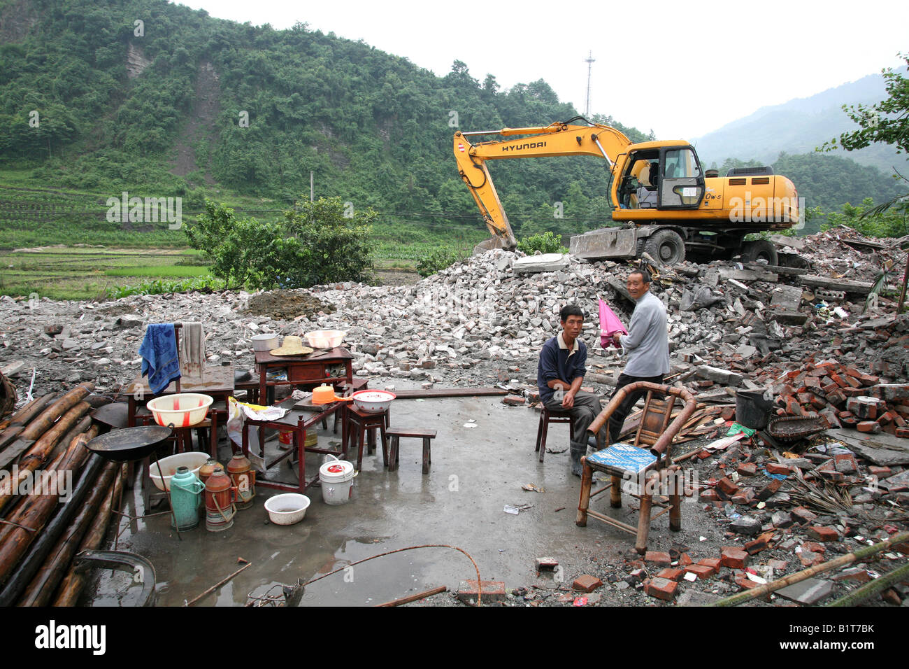 A man sits in the remains of what used to be his house in Pengzhou following the Sichuan Earthquake of 12th May 2008, China Stock Photo