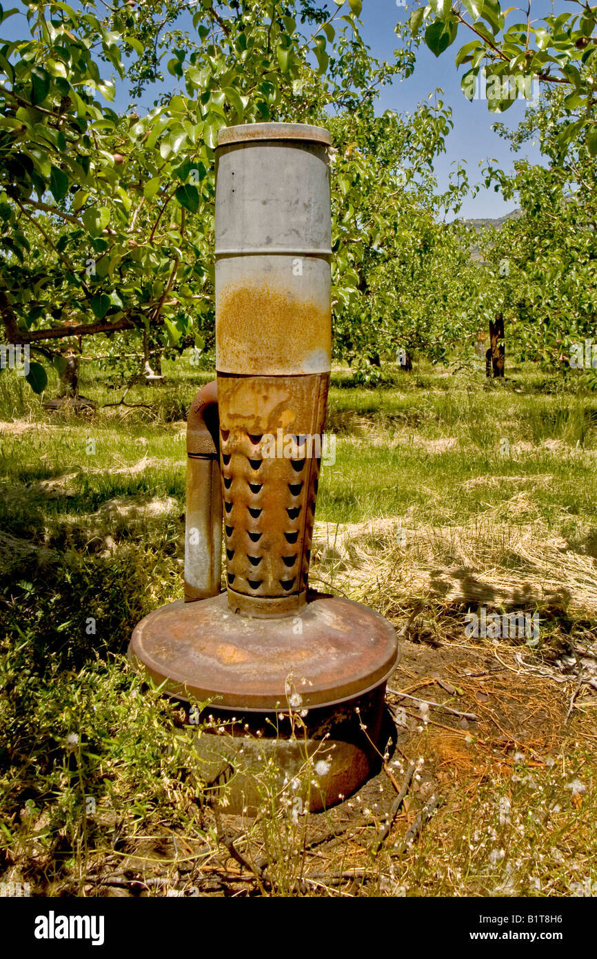 oil fired smudge pots are distributed throughout a fruit orchard in Ashland Oregon Note the side mounted rebreather pipe Stock Photo