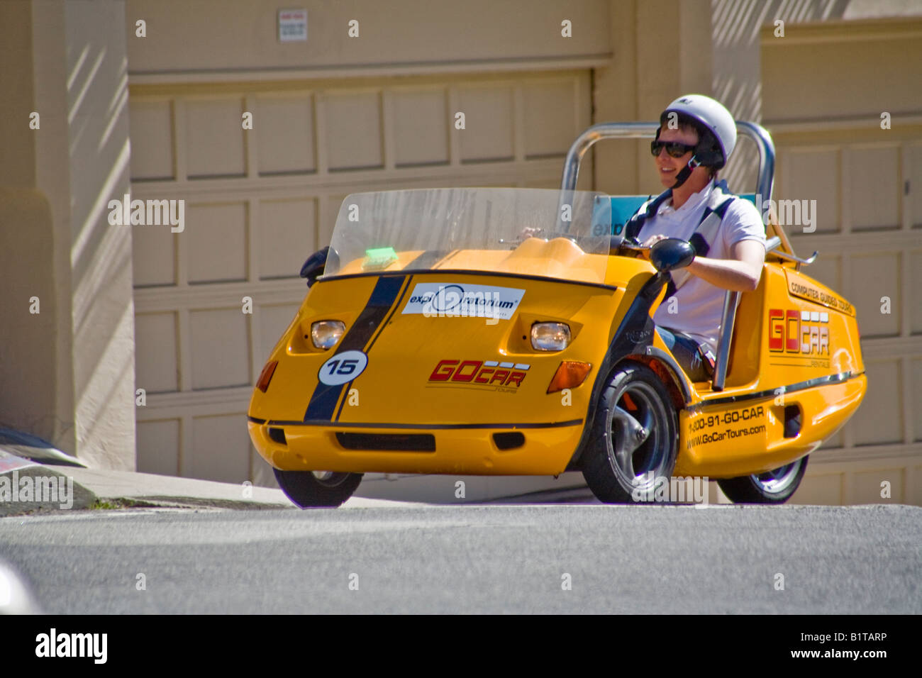A helmeted tourist sees the sights in San Francisco from a GPS equipped three wheel GoCar Stock Photo