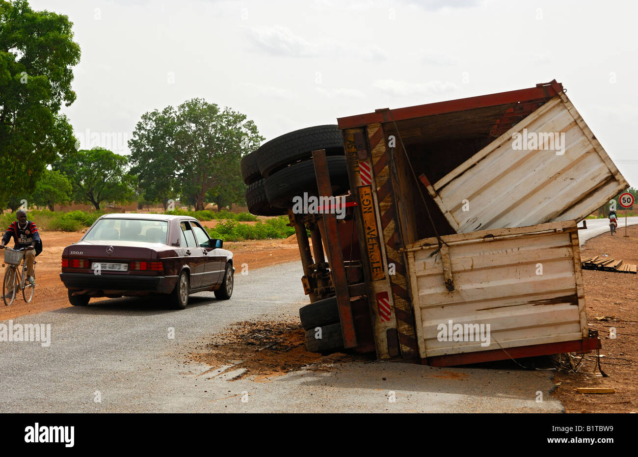 Accidented trailer of a truck lying turned over on a country road in Southern Burkina Faso, West Africa Stock Photo