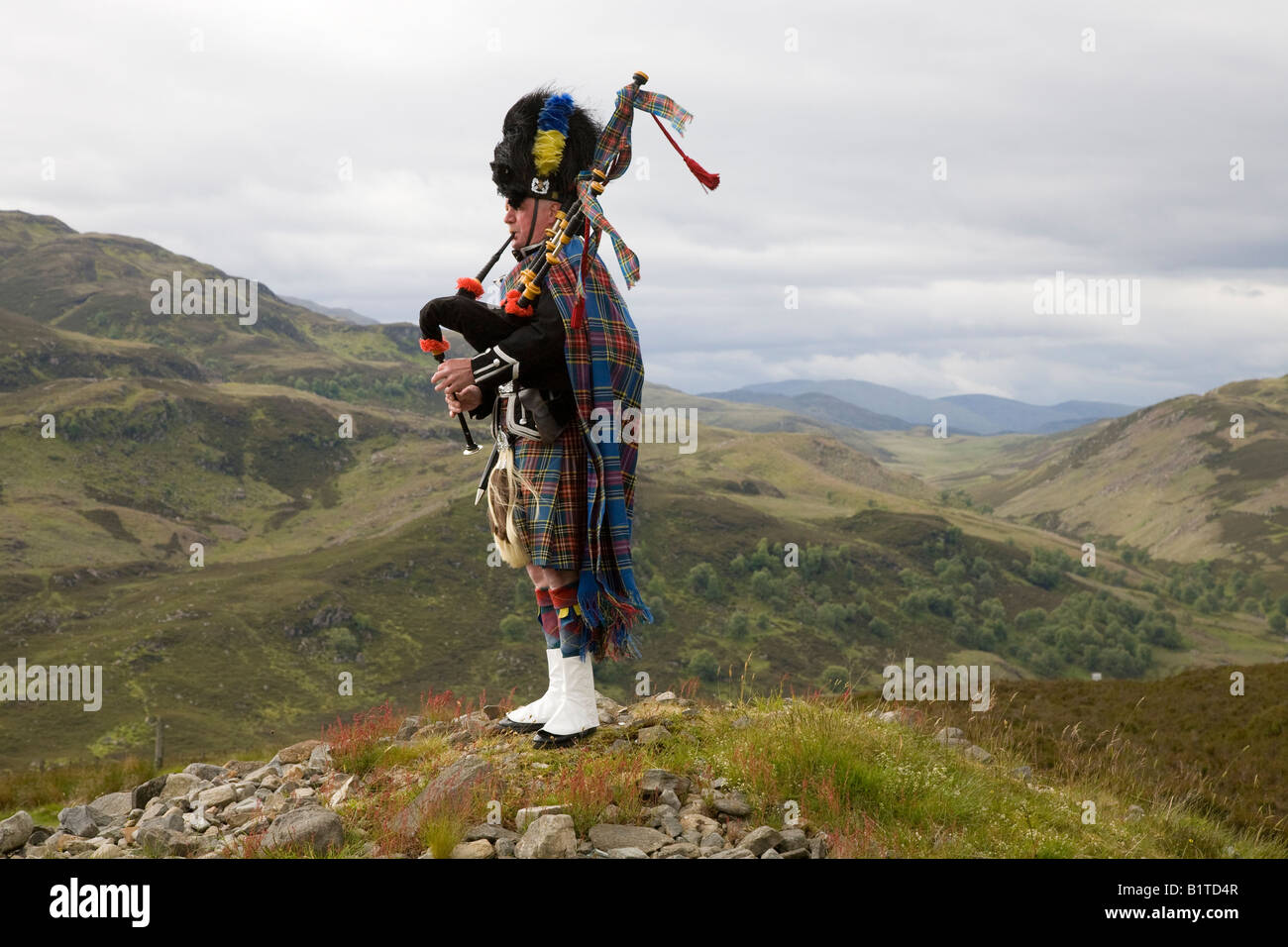 Scottish Piper playing bagpipes and wearing kilt on hill-tops of Stock ...