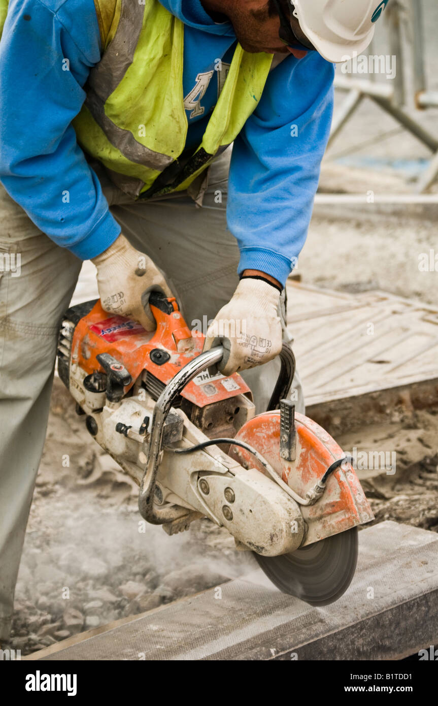 workman using an powerful cutting angle grinder tool to cut a pavement