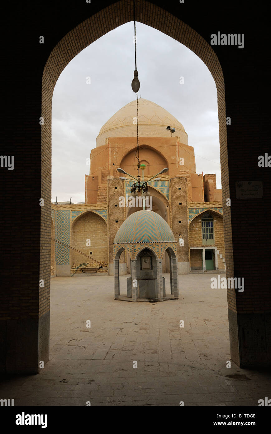 A view of a court yard inside a mosque with dome and architectural torquoise tiled water point at its centre , used for washing Stock Photo