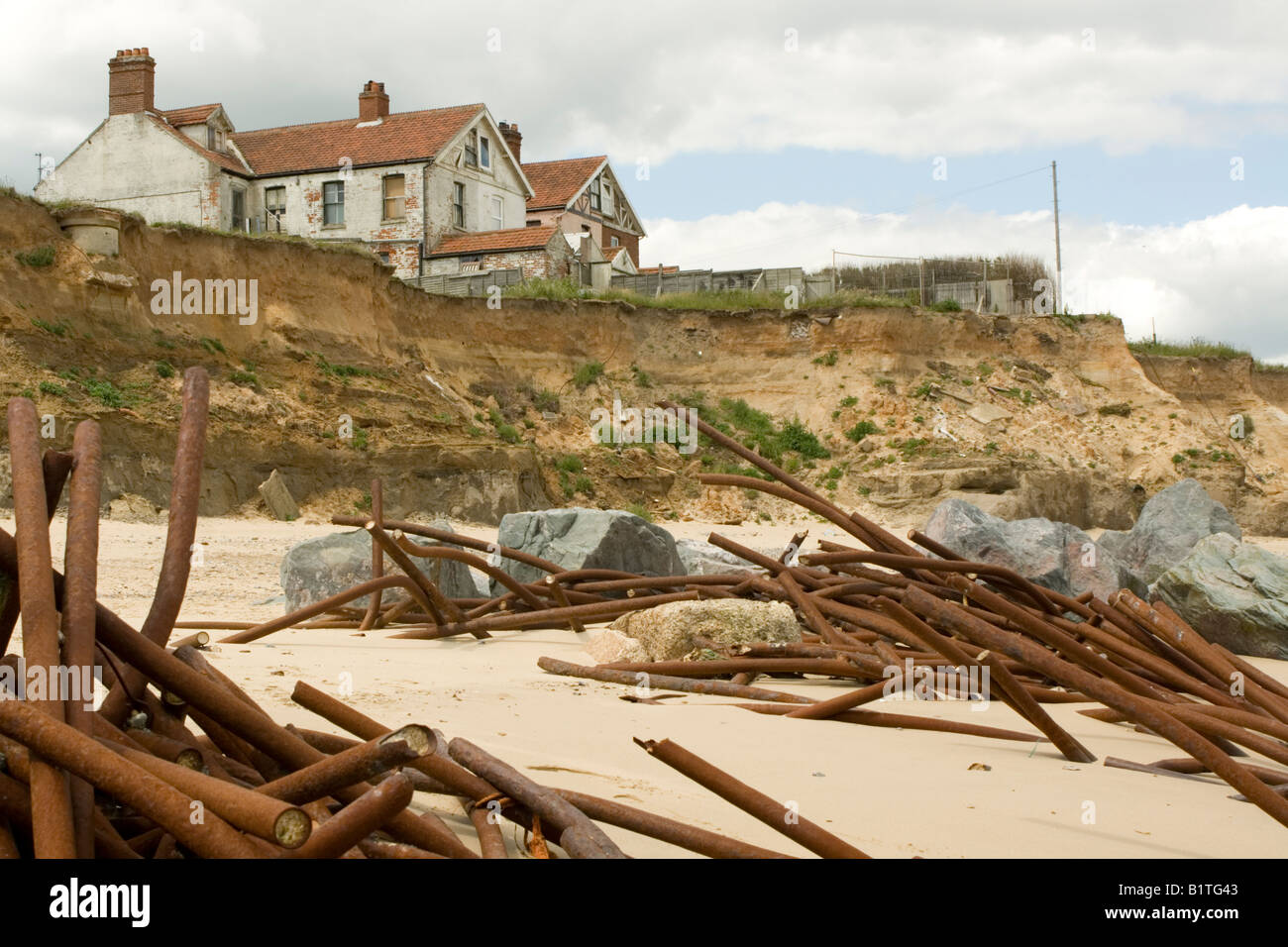 Houses on cliff edge and remains old sea defences after severe coastal erosion Happisburgh North Norfolk Coast UK Stock Photo