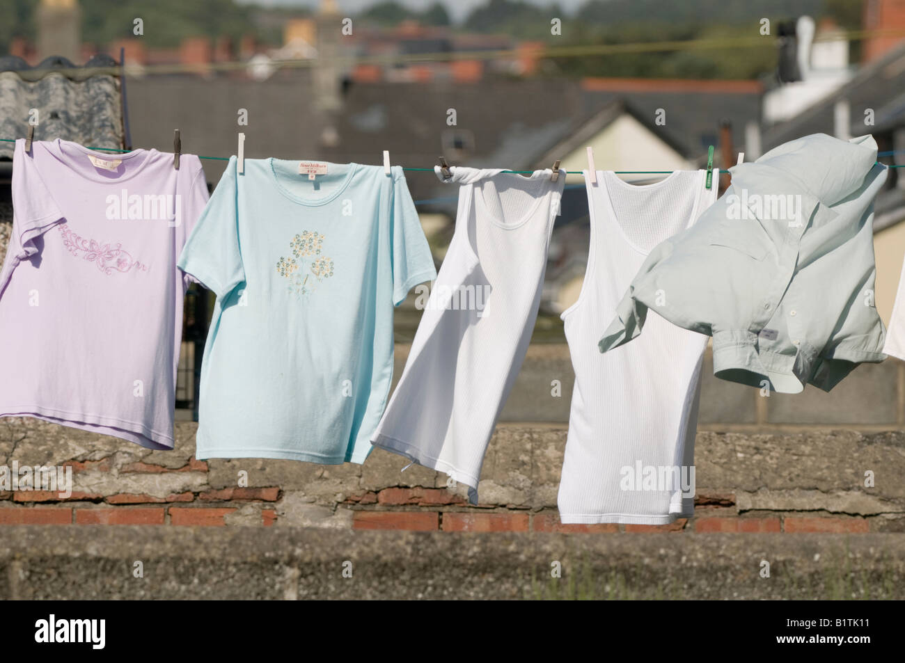 newly washed clothes - t-shirts and vests -  pegged out and drying on washing line in the breeze, UK Stock Photo