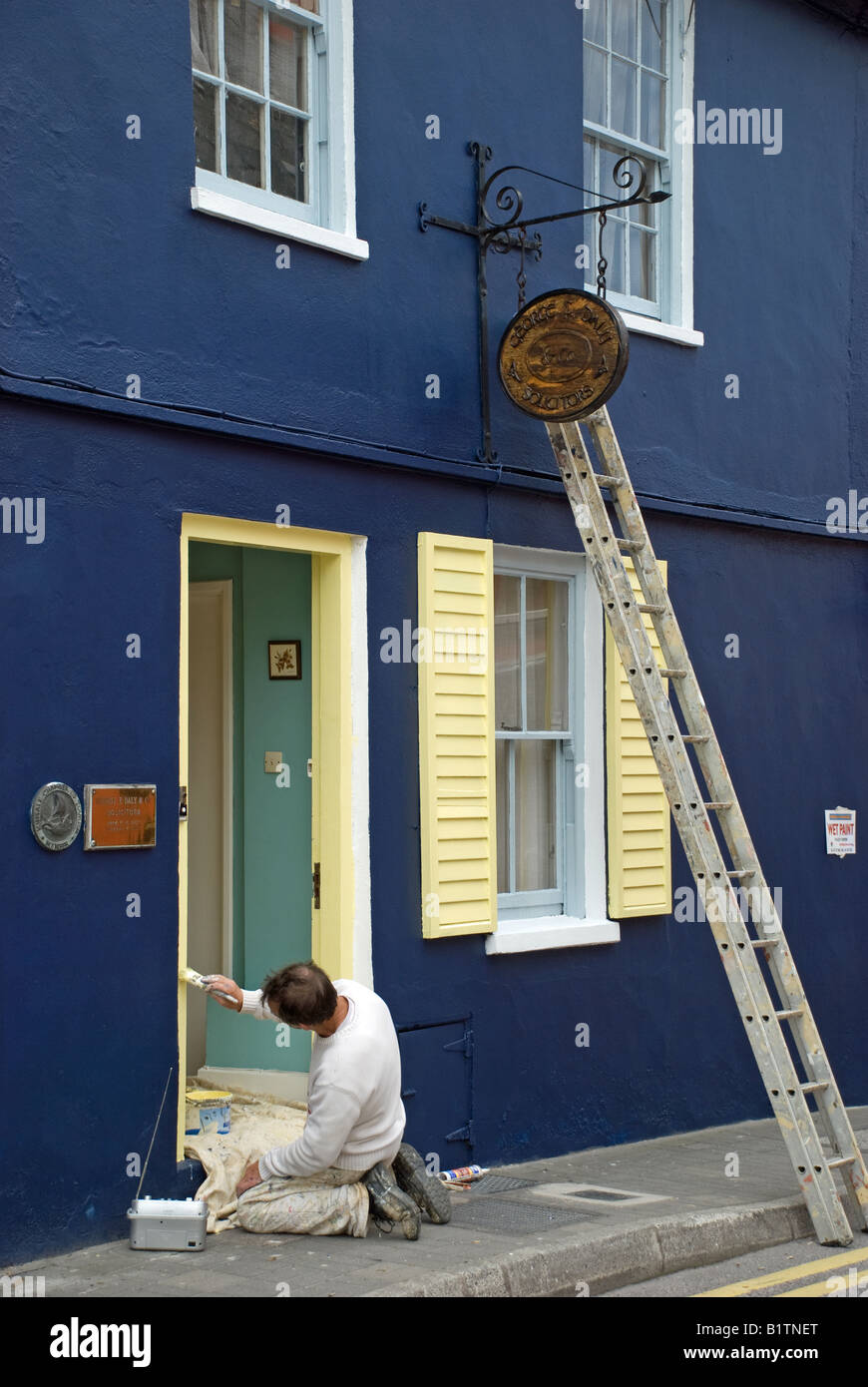 A decorator painting the doorway of a building in the centre of Kinsale, Co Cork, Ireland. Stock Photo