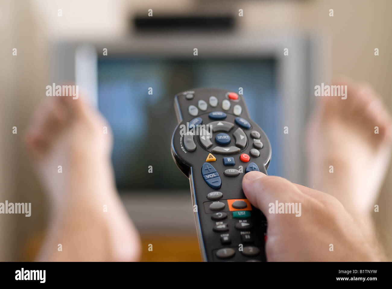 A man watches television and changes channels while relaxing on a