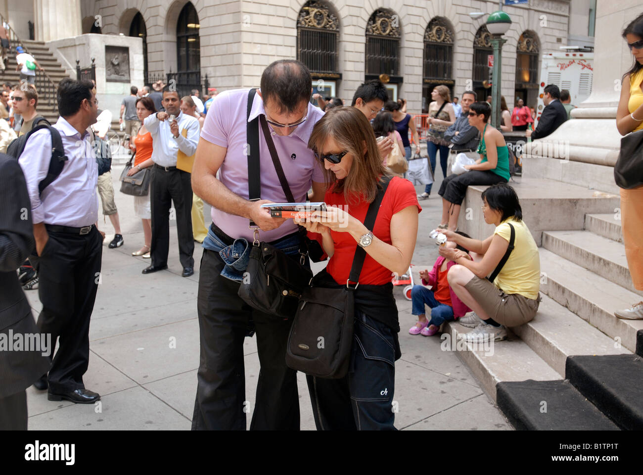 Tourists consult a guide book ion Wall Street in front of the New York Stock Exchange in New York Stock Photo