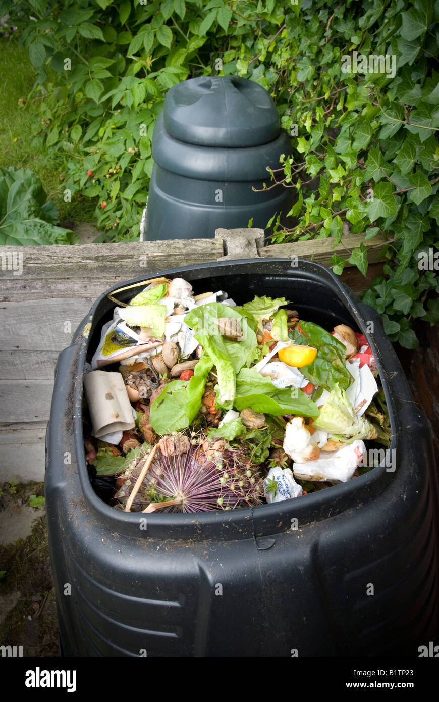 open compost bin revealing contents with closed compost bin in